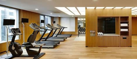 A gym with treadmills, a rowing machine, and weight racks.