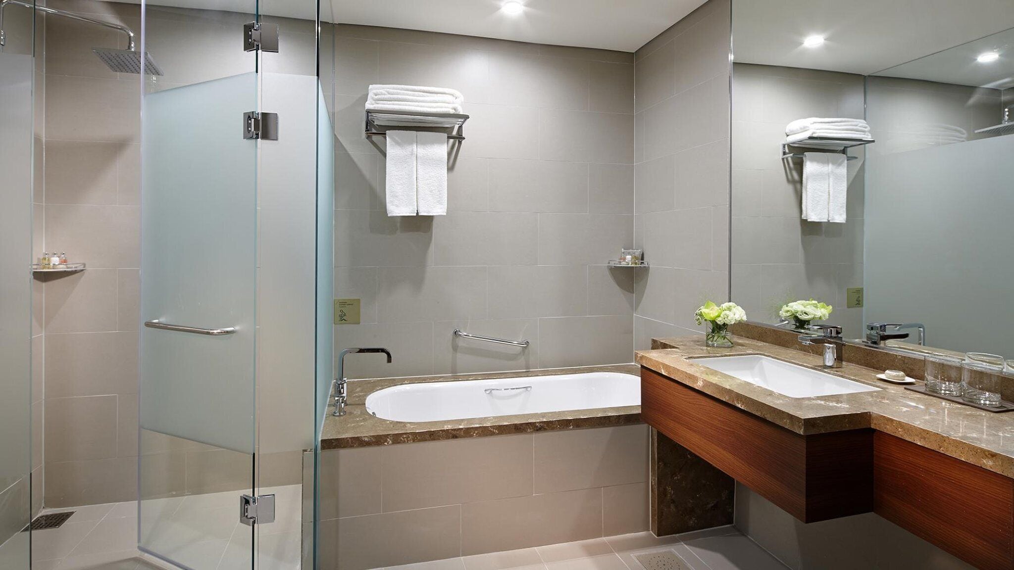 A modern bathroom with a glass-enclosed shower, a freestanding bathtub, and a vanity with a mirror.