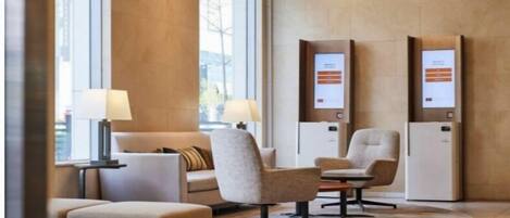 A modern lobby with seating, a large chandelier, and information kiosks.