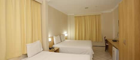 A hotel room with two beds, a desk, a chair, a small refrigerator, and a cabinet.