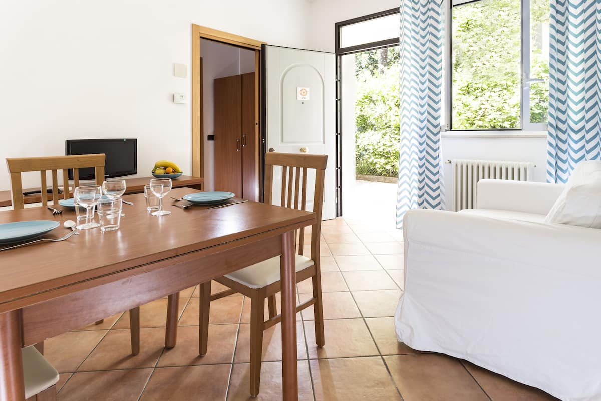A dining area with a wooden table and chairs, a television, and a bowl of fruit.