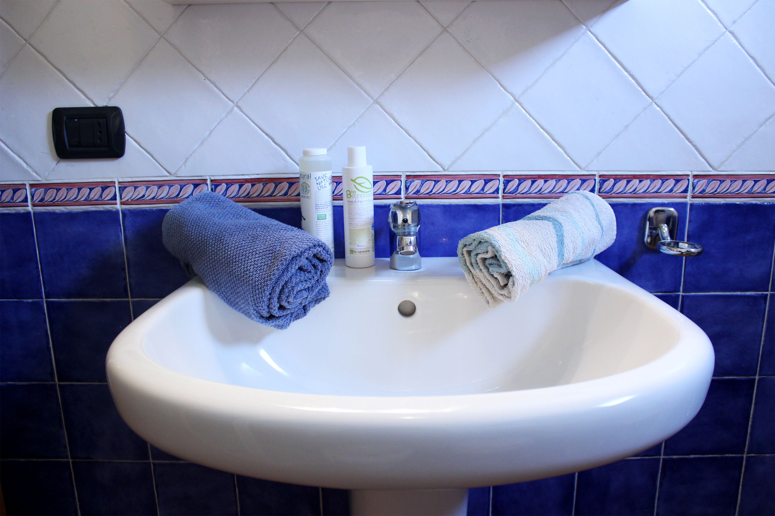 A bathroom sink with two towels, a soap dispenser, and a faucet.