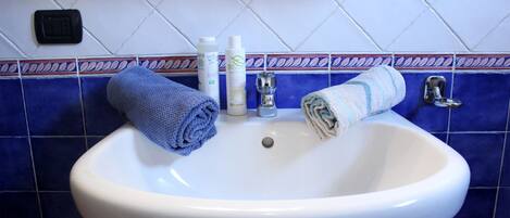 A bathroom sink with two towels, a soap dispenser, and a faucet.