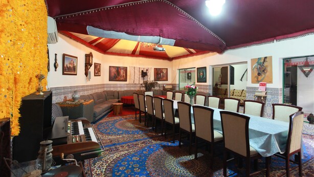 A dining area with a long table, chairs, and a patterned carpet. - Riad Asma (Taroudant)