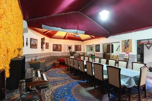 Comedor con una mesa larga, sillas y alfombra estampada.
