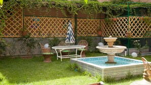 A garden with a tiled fountain, a table with chairs, and a lattice fence. - Riad Asma (Taroudant)
