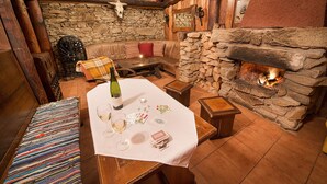 A cozy interior with a stone fireplace, a leather sofa, and a table set for dining. - Penzion Farma U Mauritzů (Stozec)