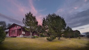 A rustic log cabin with a stone foundation, surrounded by a grassy yard and large trees. - Penzion Farma U Mauritzů (Stozec)