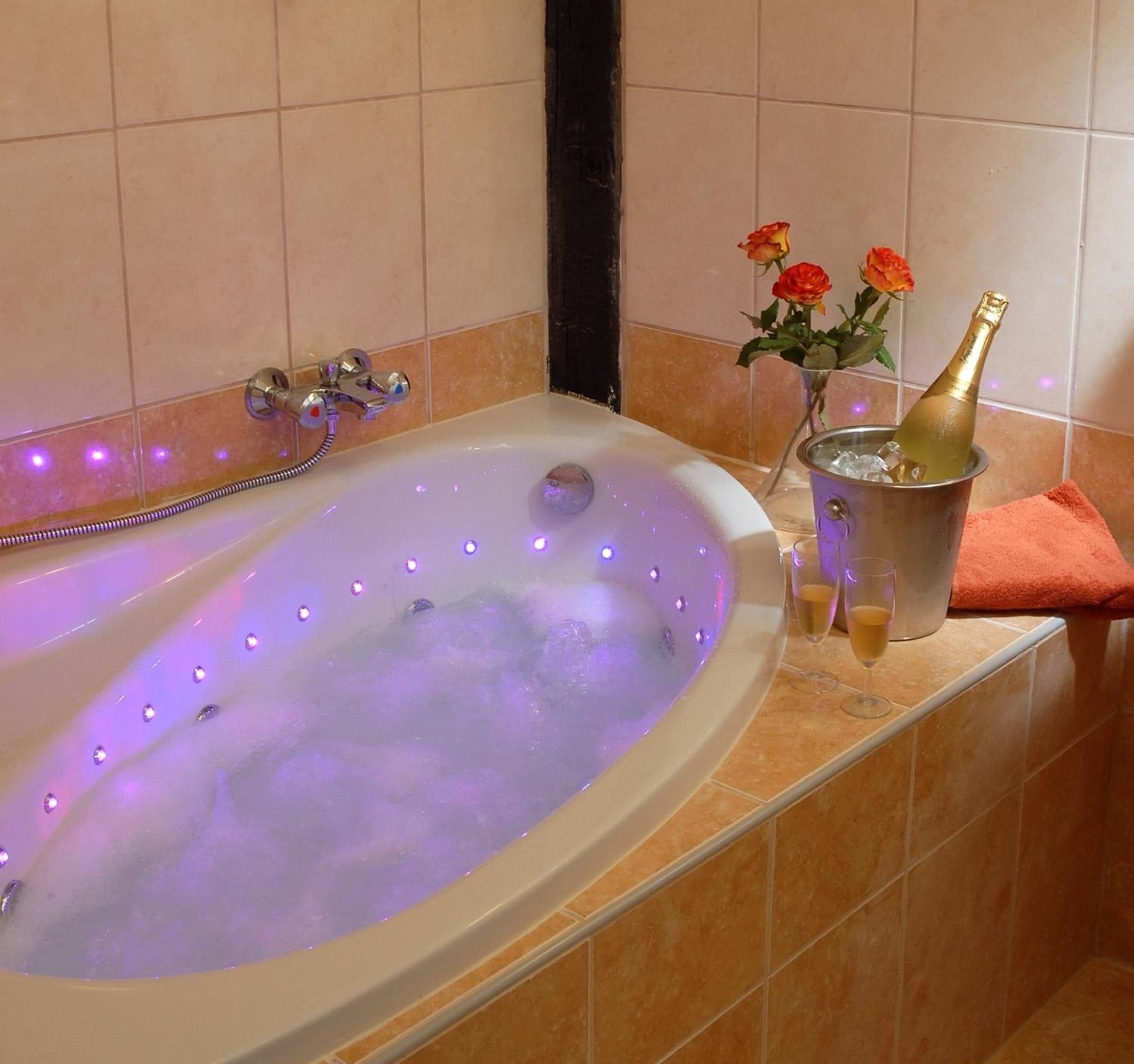 A bathtub with a champagne bottle and flowers.