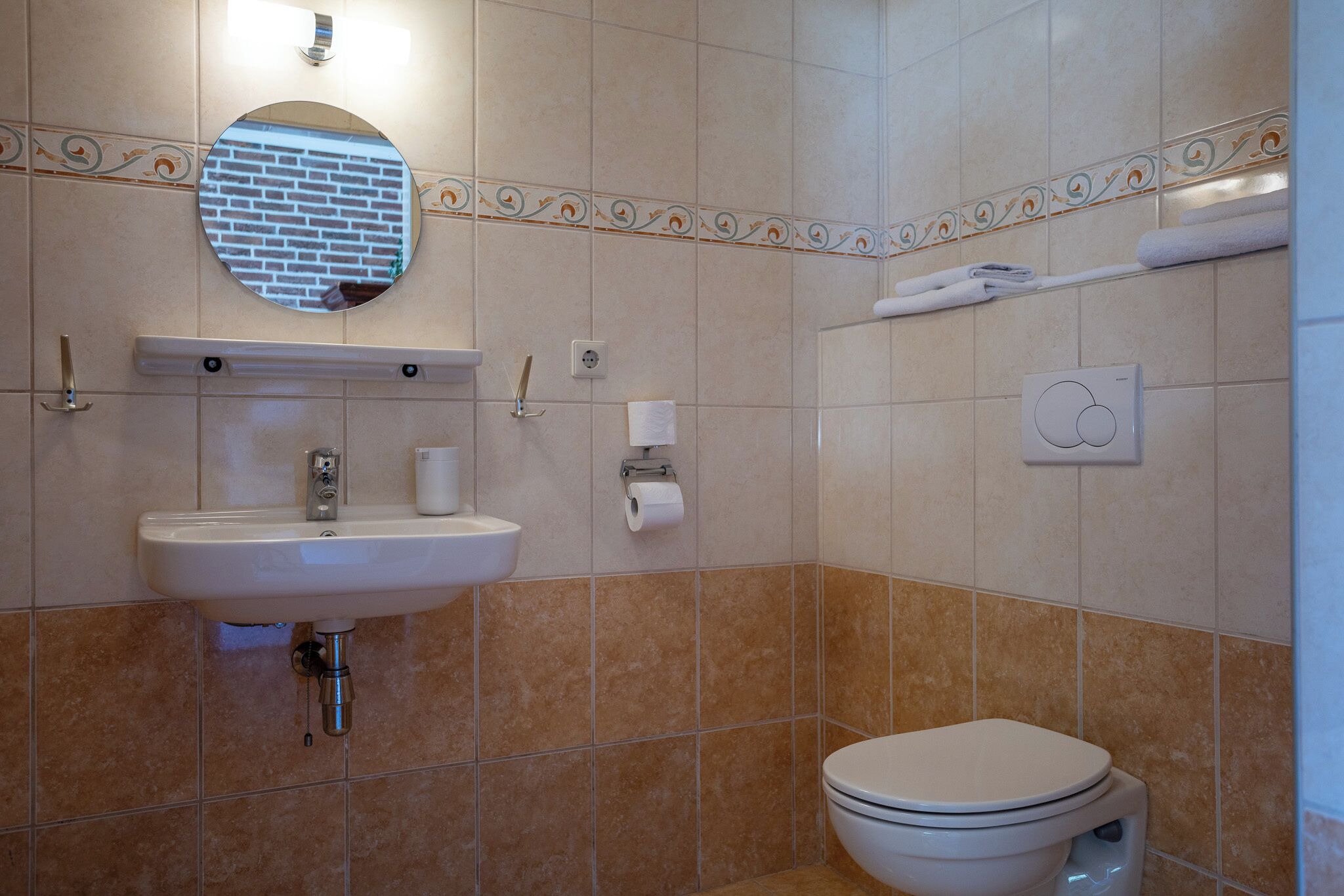 A bathroom with a sink, mirror, toilet, and towel rack.