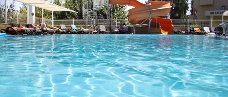 Alberca al aire libre, sombrillas en la alberca y camastros