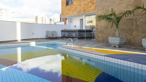 A rooftop pool with a tiled edge, a brick building, and two lounge chairs. - Carlton Plaza Poços de Caldas (Poços de Caldas)