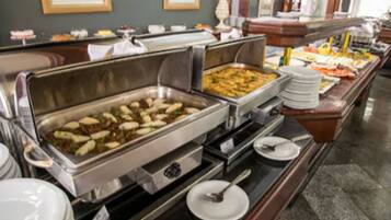 Buffet com diversos alimentos e utensílios de servir.