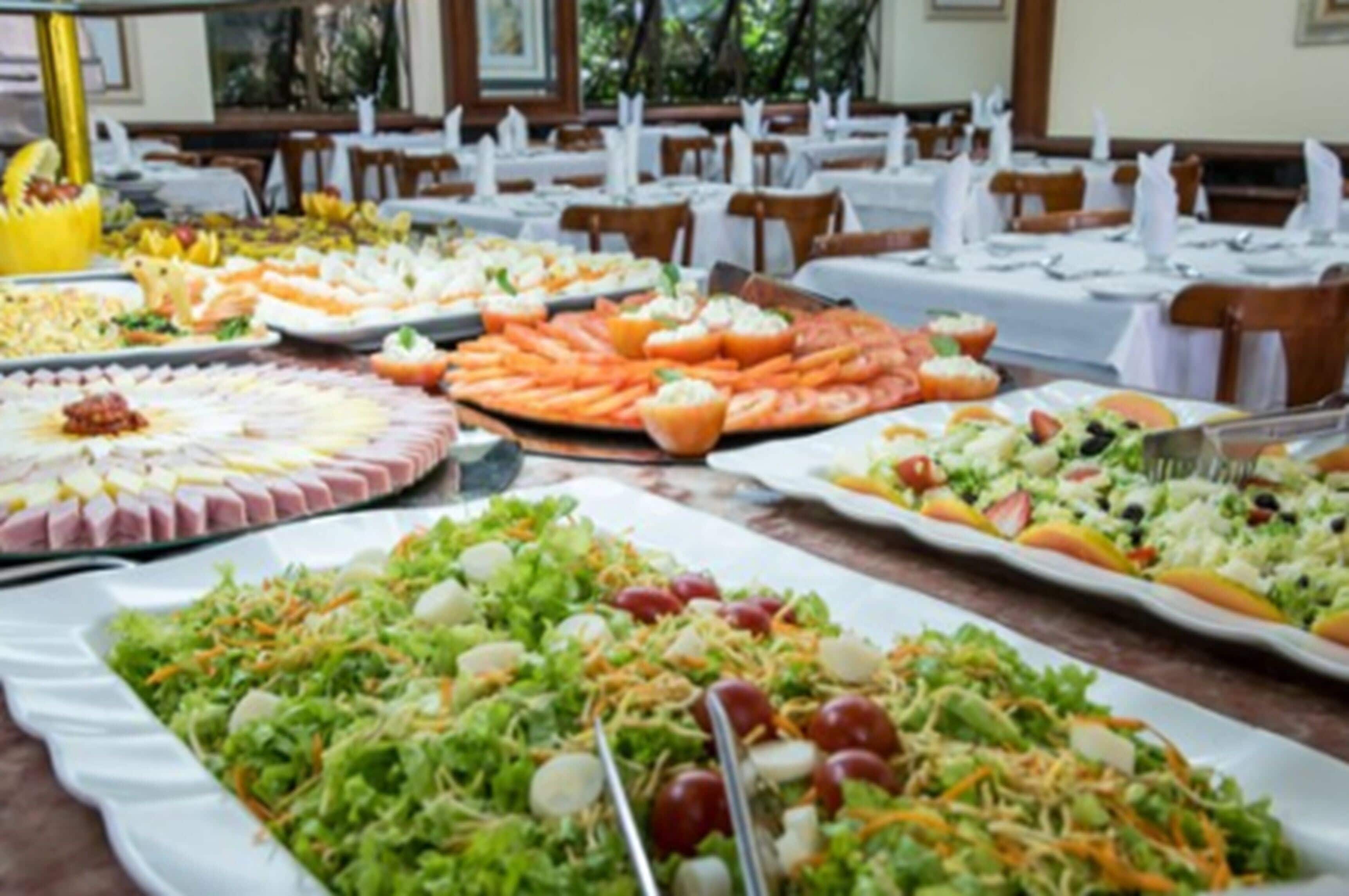 A buffet with various dishes including salads, fruits, and appetizers.
