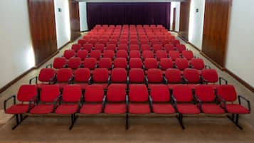A theater with rows of red seats and a stage at the front.