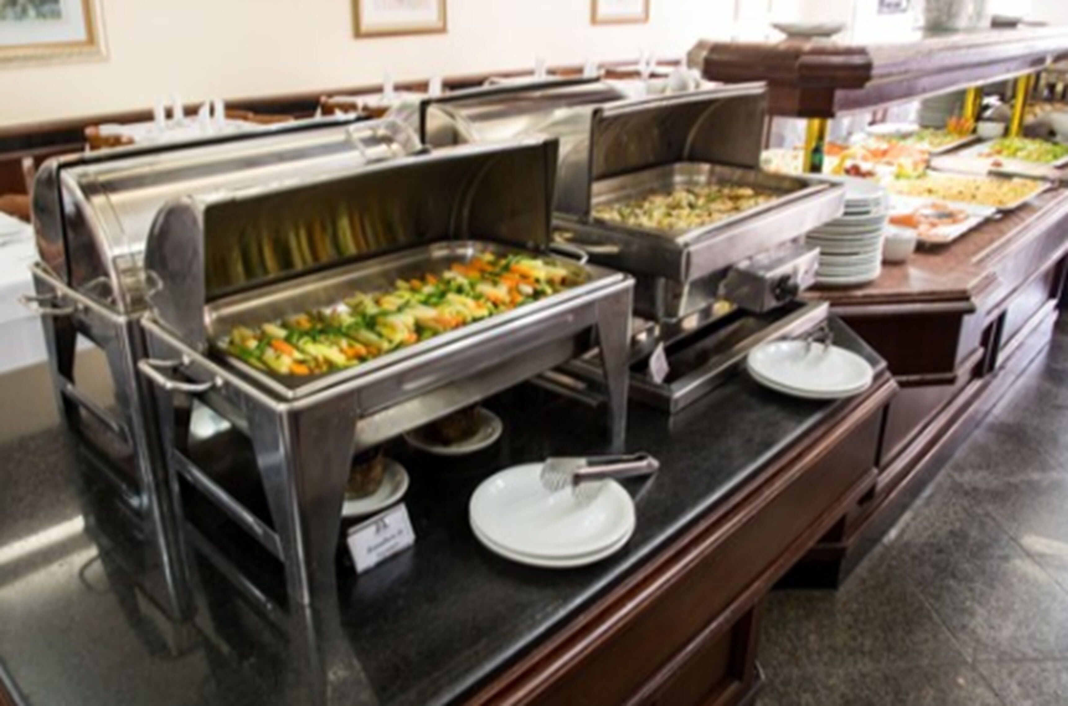 A buffet setup with multiple serving stations, including trays of assorted foods and plates for guests.