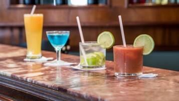 A bar with four different drinks, each with a straw and a lime wedge.