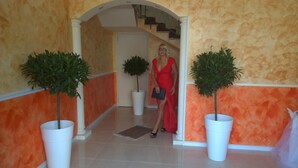 A hallway with a red and beige color scheme, white columns, and potted plants. - Bed and breakfast delle palme (Trapani)