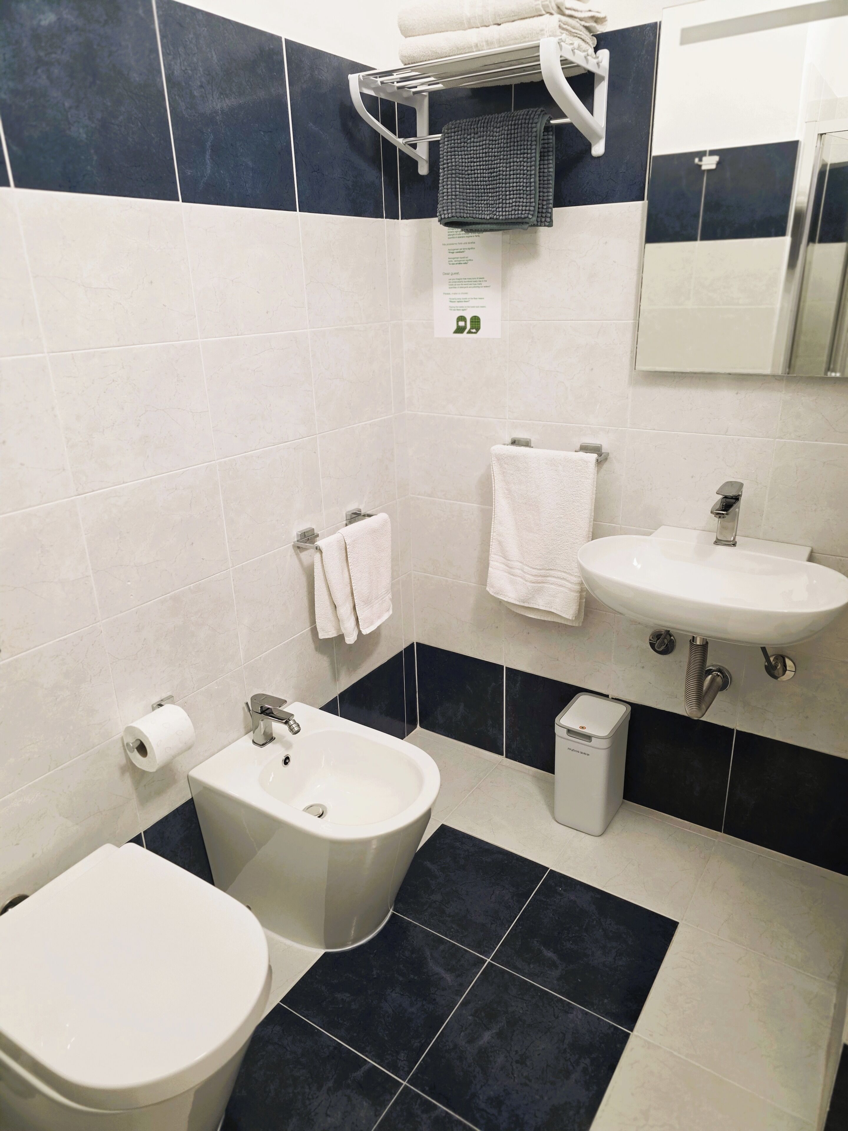 Une salle de bain moderne équipée de toilettes, d’un bidet, d’un lavabo et d’un porte-serviettes.