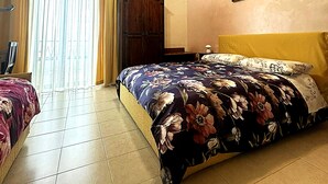 A bedroom with a bed, a ceiling fan, a window with curtains, an air conditioning unit, and a painting on the wall. - Bed and breakfast delle palme (Trapani)