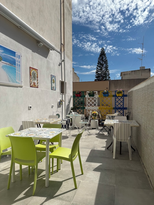 An outdoor patio with tables and chairs, a decorative fence, and a view of the sky.