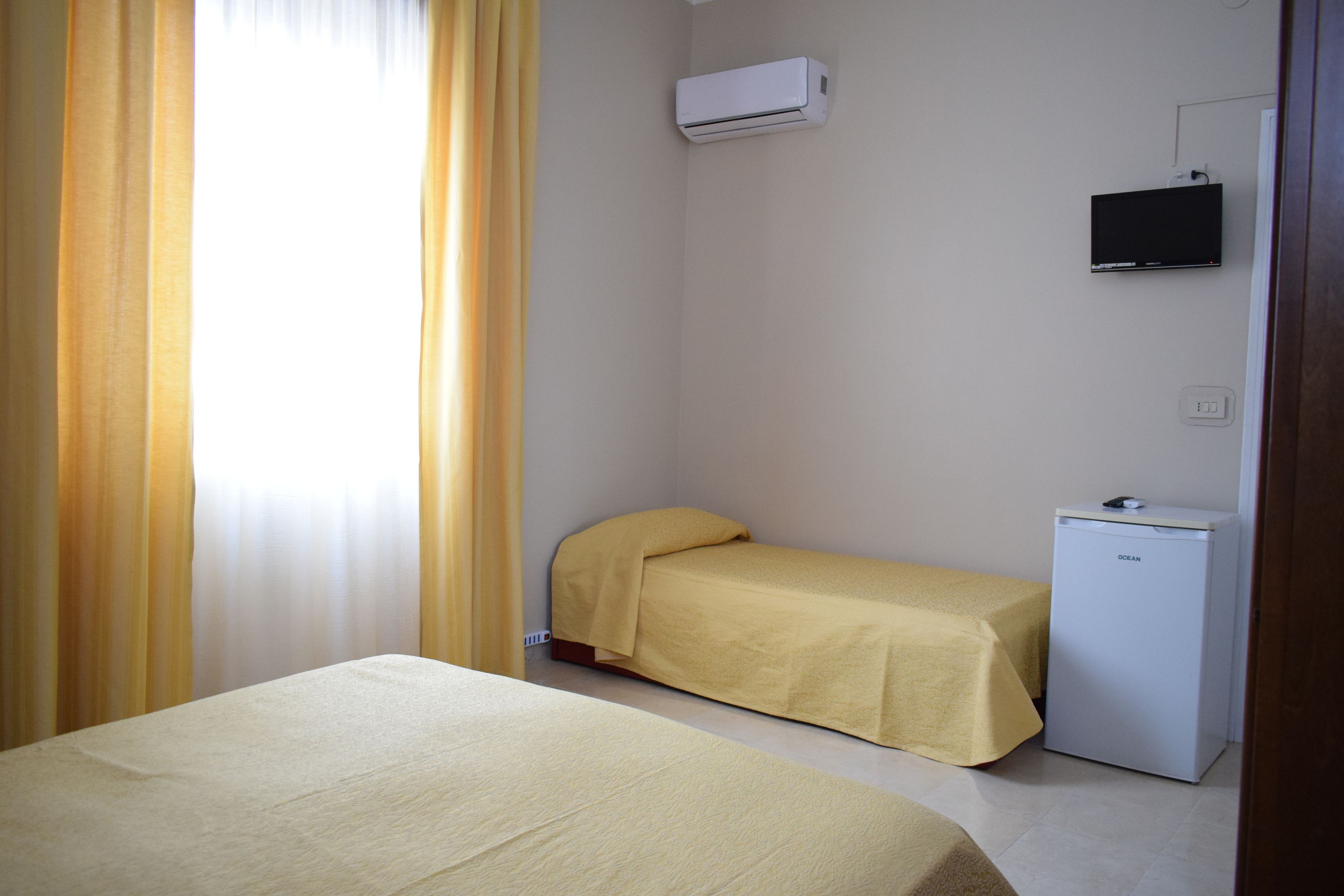 A small room with two beds, a TV, and a refrigerator.