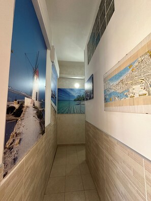 A hallway with tiled walls, a map mural, and a windmill painting.