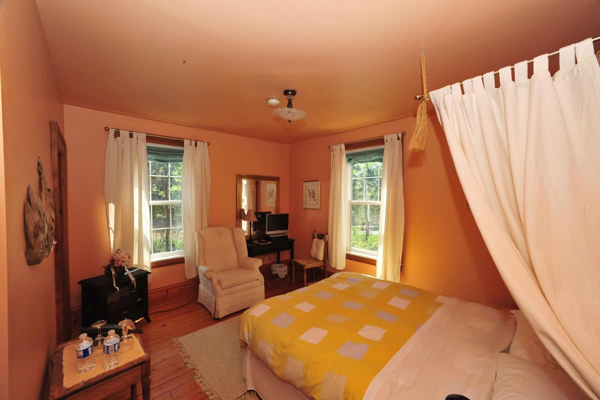 Un dormitorio con cama, escritorio, silla y ventana con cortinas.