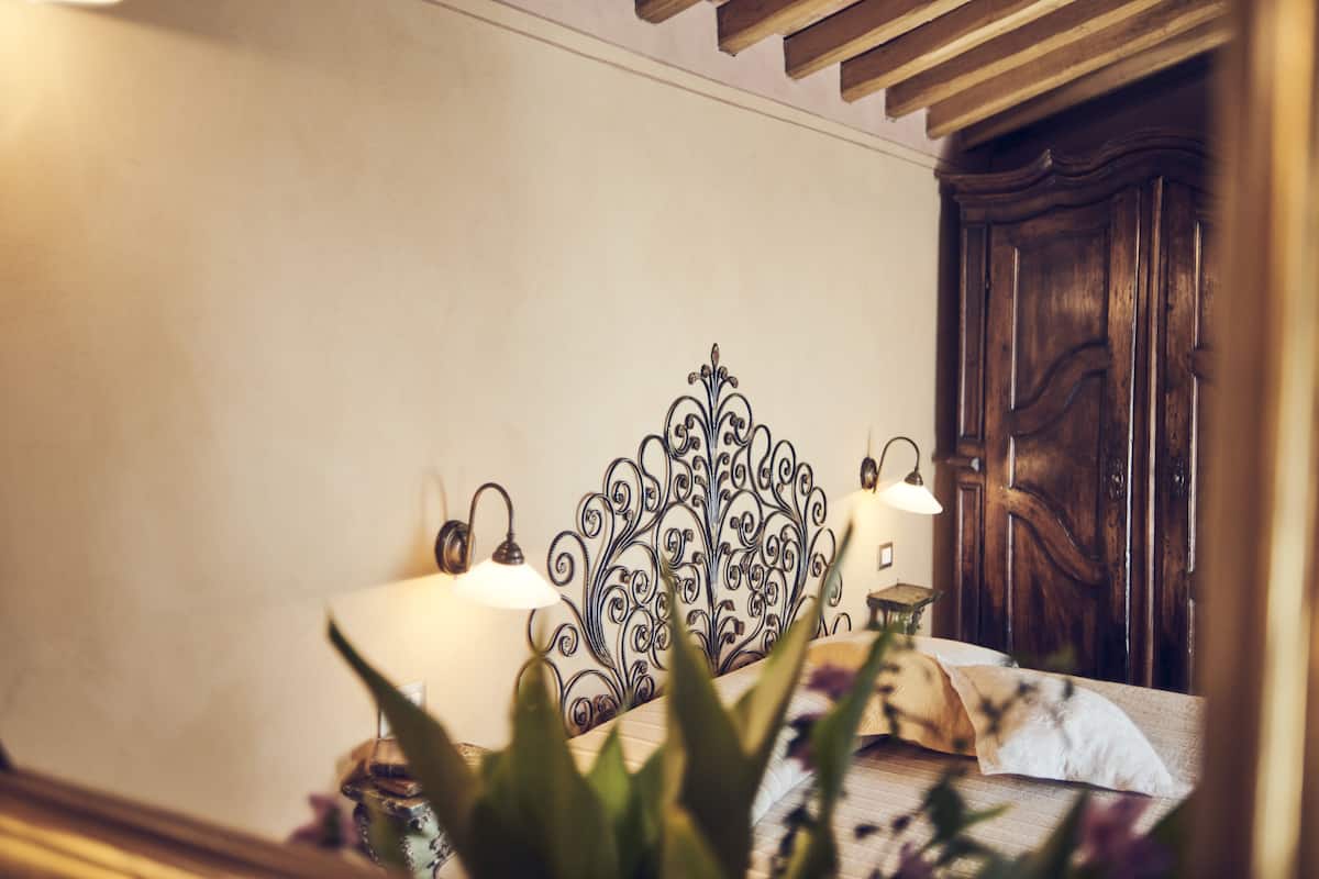 A bedroom with a bed, a wooden wardrobe, and a decorative metal headboard.