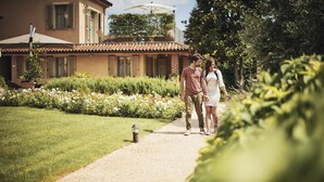 A pathway leading to a building with a tiled roof and a garden with flowers and plants. - Antica Locanda SanPietro (Govone)