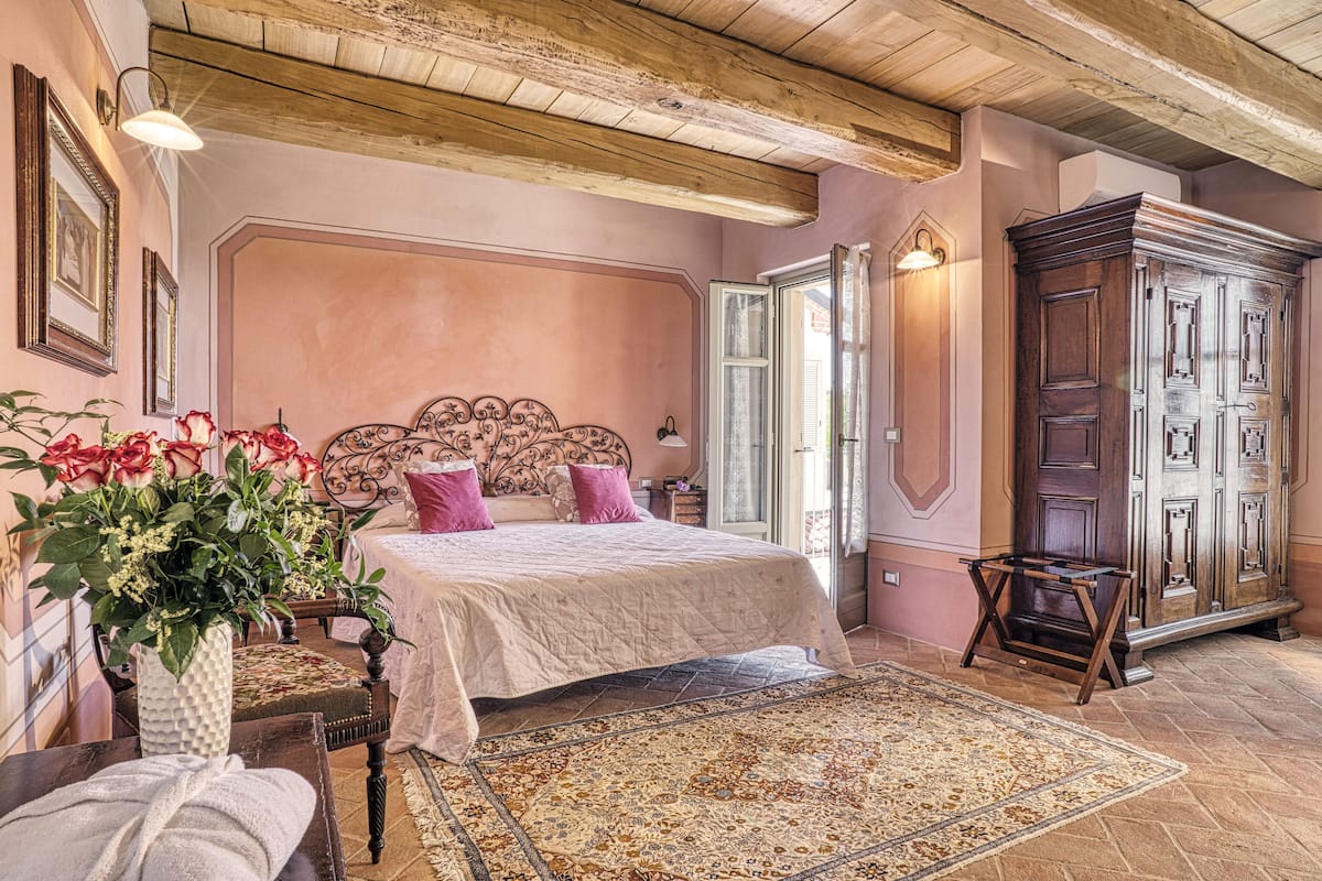 A bedroom with a large bed, a wooden wardrobe, and a decorative headboard.