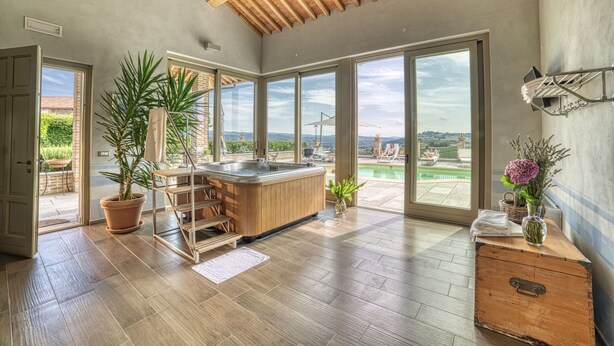 A spacious room with a wooden ceiling, large windows, a hot tub, and a view of the outdoors. - Antica Locanda SanPietro (Govone)
