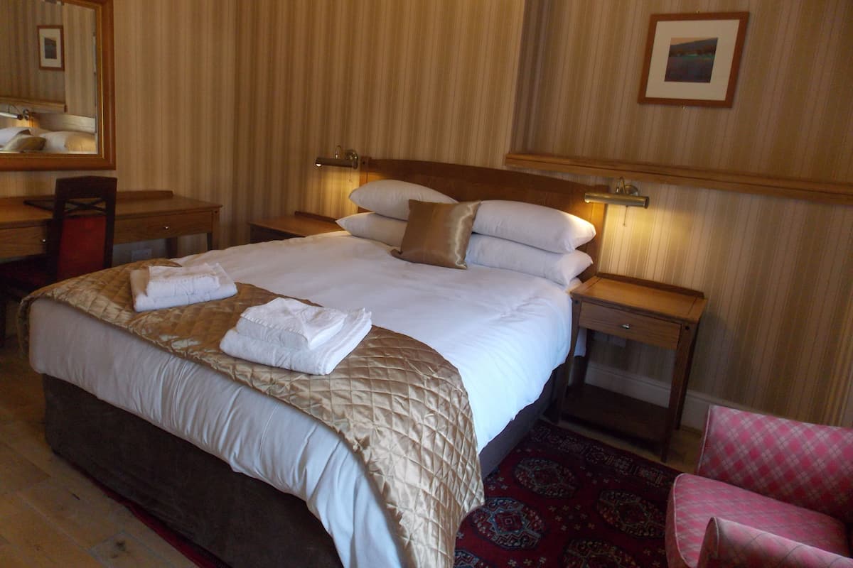 Una habitación de hotel con una cama grande, un escritorio, una silla y una mesita.