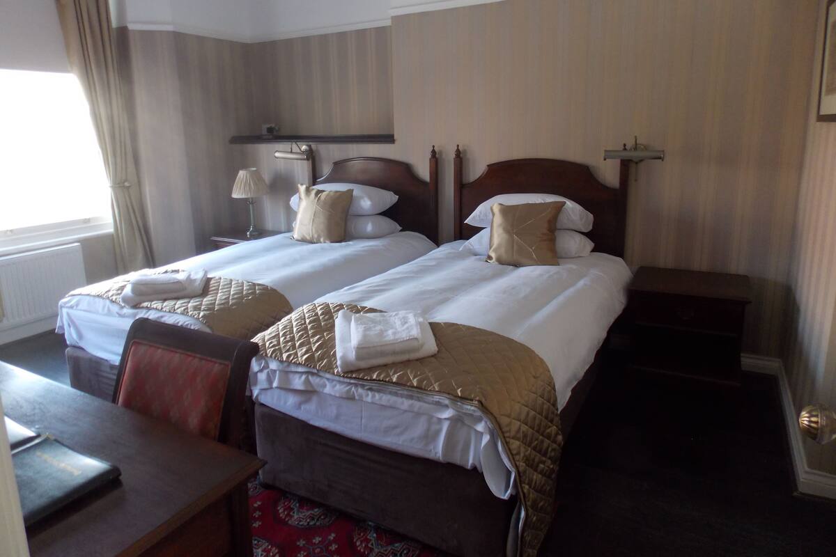 Habitación de hotel con dos camas, un escritorio y una silla.