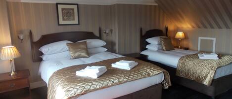 A hotel room with two beds, a nightstand, a lamp, and a framed picture on the wall.