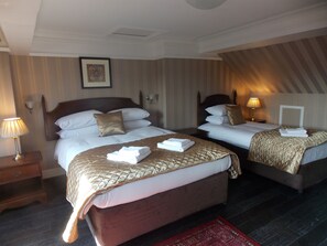 Ett hotellrum med två sängar, ett nattduksbord, en lampa och en inramad tavla på väggen.