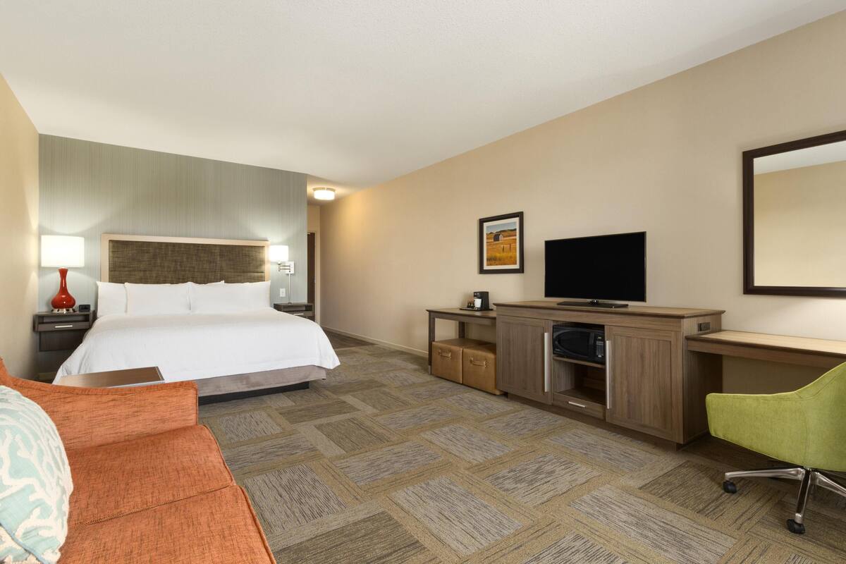 A hotel room with a bed, a desk, a television, and a chair.