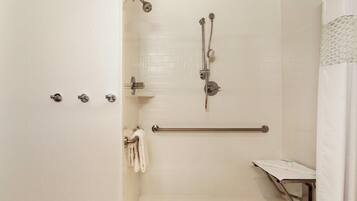 A shower with a grab bar, a towel rack, and a handheld showerhead.