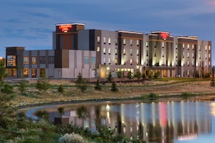 A modern hotel with a flat roof, multiple floors, and a sign indicating it is a Hampton Inn.