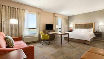 A hotel room with a bed, a desk, a chair, a television, and a window with curtains.