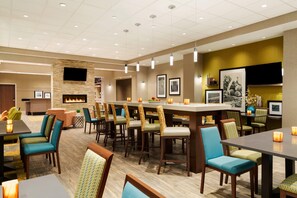 A hotel lobby with a bar area, seating, a fireplace, and artwork on the walls. - Hampton Inn by Hilton Edmonton/Sherwood Park (Sherwood Park)