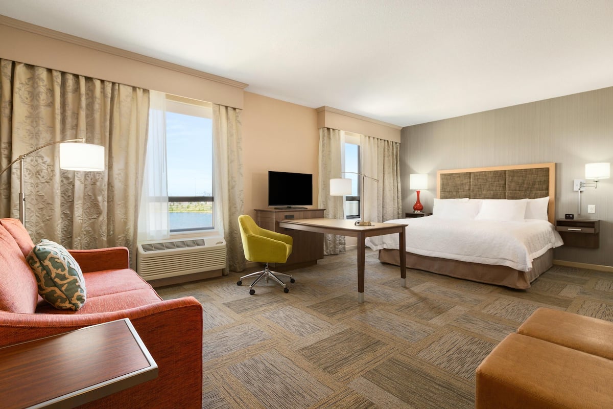A hotel room with a bed, a desk, a chair, a television, and a window with curtains.