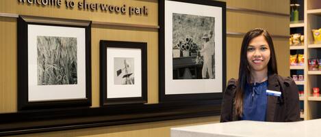 A reception desk with a welcome sign, framed black and white photographs, and a shelf with snacks.