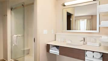 A modern bathroom with a glass-enclosed shower, a sink with a mirror above, and neatly arranged towels.