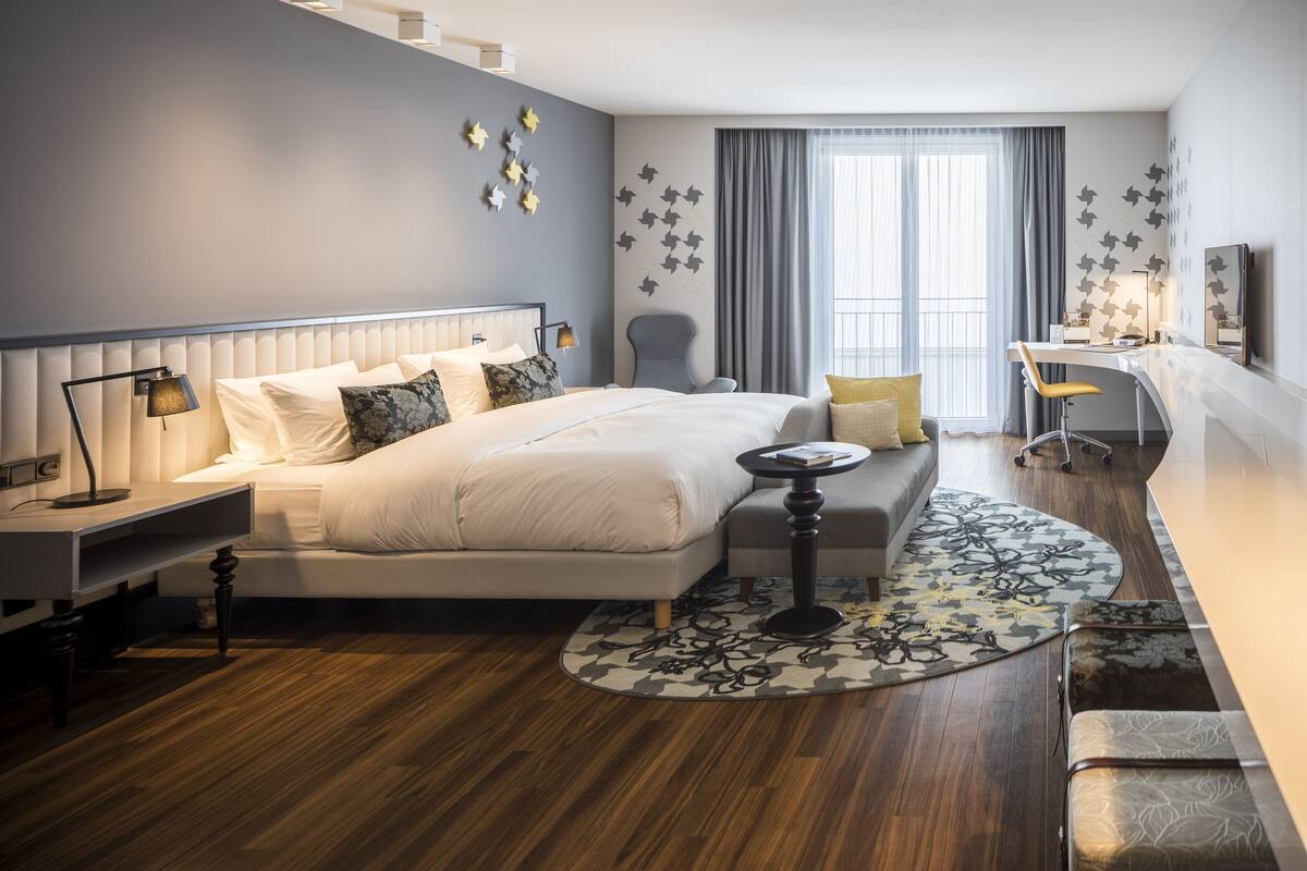 Une chambre d’hôtel moderne, dotée d’un grand lit, d’un bureau et d’une chaise.