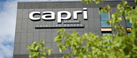 A building with a sign that reads "Capri by Fraser hotel residences".