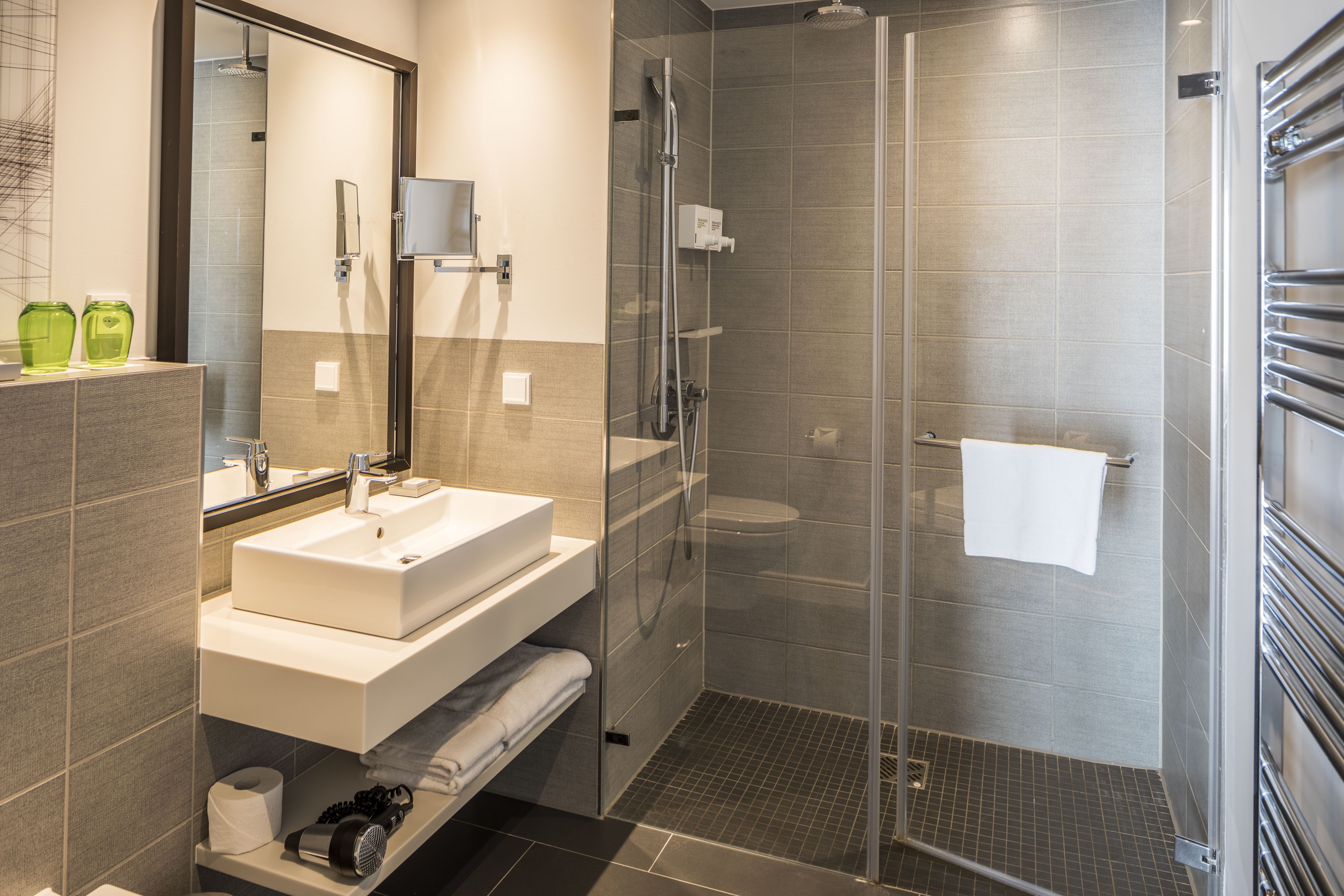 Une salle de bain moderne avec une douche à parois de verre, un lavabo blanc et un miroir au-dessus.