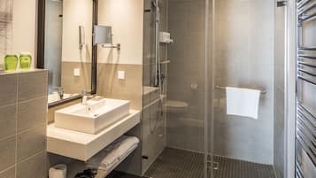 A modern bathroom with a glass-enclosed shower, a white sink, and a mirror above it.