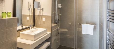 A modern bathroom with a glass-enclosed shower, a white sink, and a mirror above it.