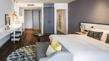 Quarto de hotel moderno com uma cama grande, um sofá, uma escrivaninha e um closet espaçoso.